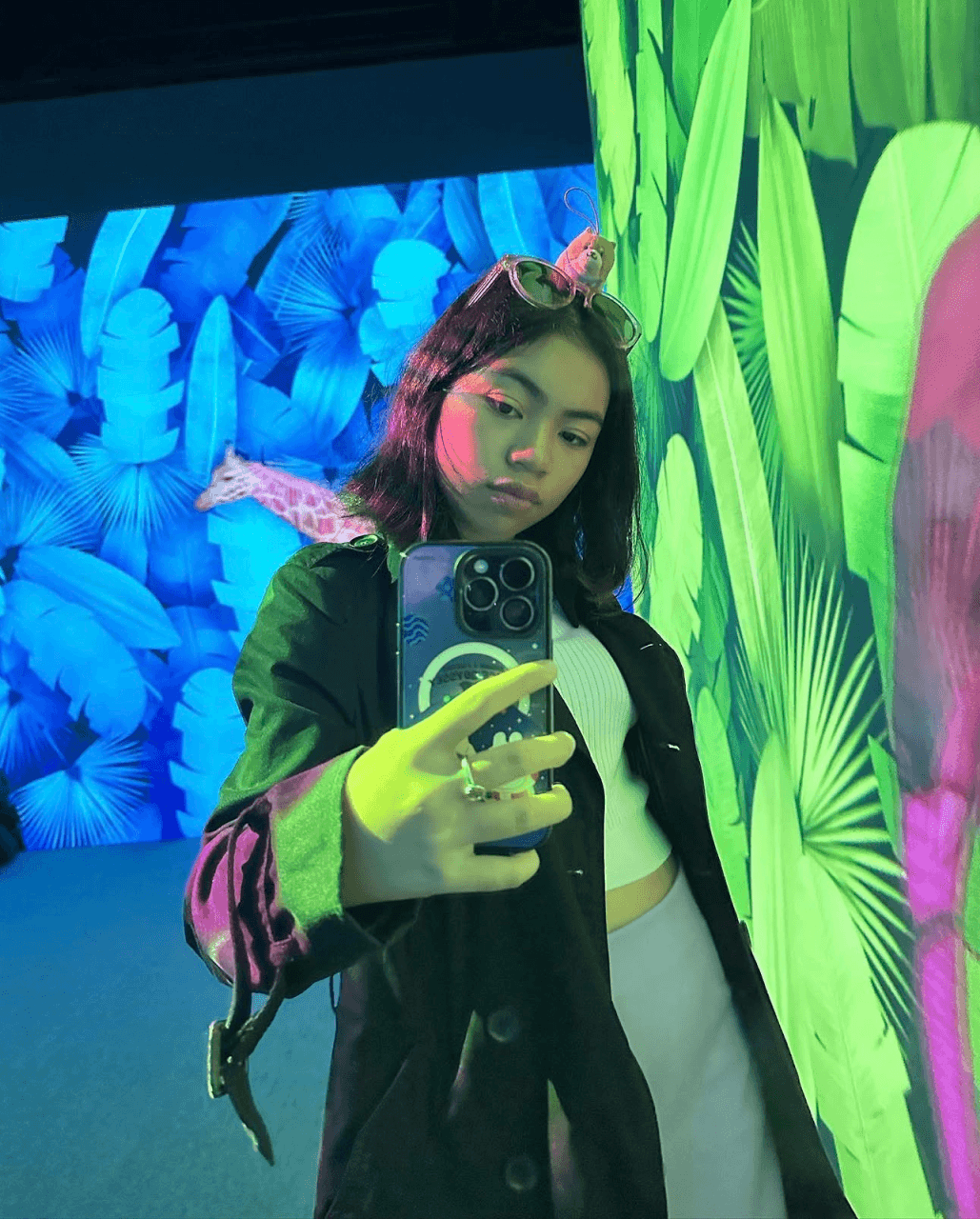 Audrey taking a mirror selfie against a tropical leaf backdrop