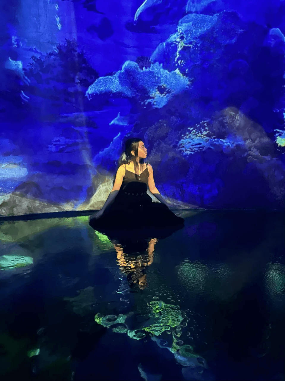 Audrey sitting beside a glowing blue aquarium reflection