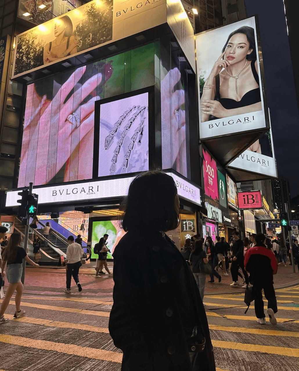 Audrey standing before a Bvlgari billboard in a busy city crosswalk