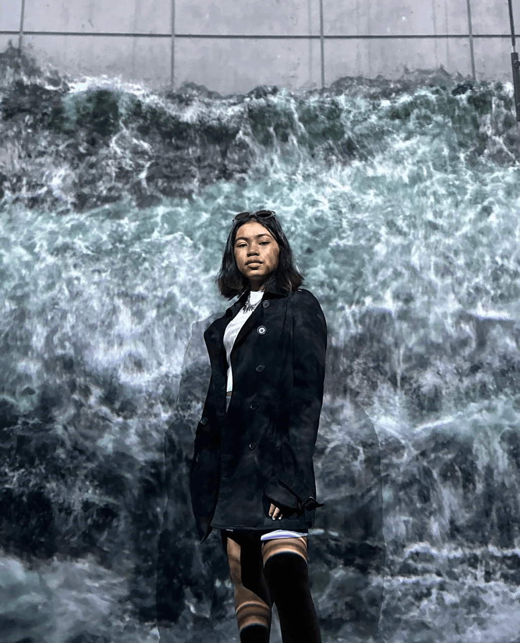 Audrey posing in front of a projected ocean wave mural